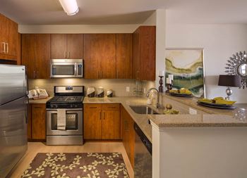 a kitchen with stainless steel appliances and wooden cabinets at Reveal Hackensack apartments
